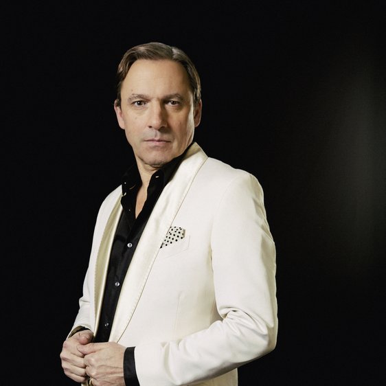 Rocko Schamoni im weißen Anzug und schwarzen Hemd