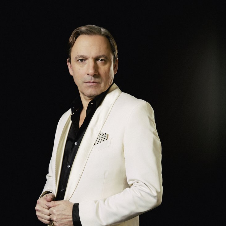 Rocko Schamoni im weißen Anzug und schwarzen Hemd